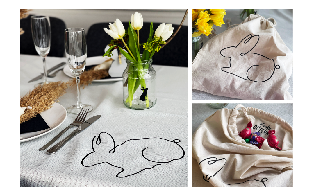 Ostertisch mit Hasen-Linienmotiv auf Tischdecke, Stoffbeutel mit gleichem Motiv und Frohe Ostern-Aufdruck innen, gefüllt mit Schokoeiern