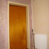 Geschlossene orangebraune Holztür mit weißer Zarge im Flur neben einem Heizkörper, Ausgangszustand vor dem Bekleben mit Folie