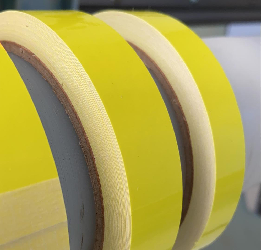 Bandes étroites découpées dans un film vinyle 3M Scotchcal jaune fluorescent, enroulées autour de mandrins en carton ; gros plan sur les bords de coupe nets