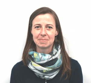 Andrea Hammerl, neue Mitarbeiterin in der Buchhaltung, mit langen braunen Haaren, dunklem Oberteil und bunt gemustertem Schal vor weißem Hintergrund