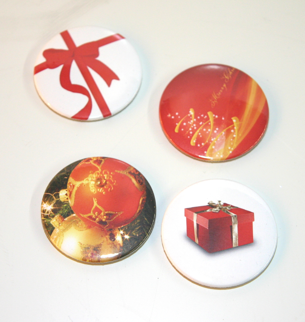 Vier selbstgemachte Magnetbuttons mit Weihnachtsmotiven: rote Schleife, Schriftzug Merry Christmas, Christbaumkugeln, rotes Geschenk