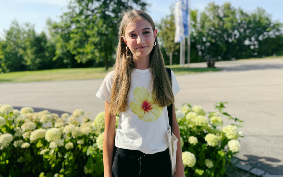 Mädchen trägt beim Ferienpass ein weißes T-Shirt mit DTF-Druck einer gelben Hibiskusblüte, im Hintergrund weiße Hortensien