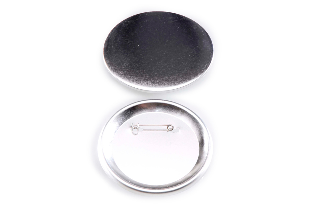 Unbedruckter runder Button, 75 mm: Vorderseite aus Metall und Rückseite mit Sicherheitsnadel auf weißem Hintergrund