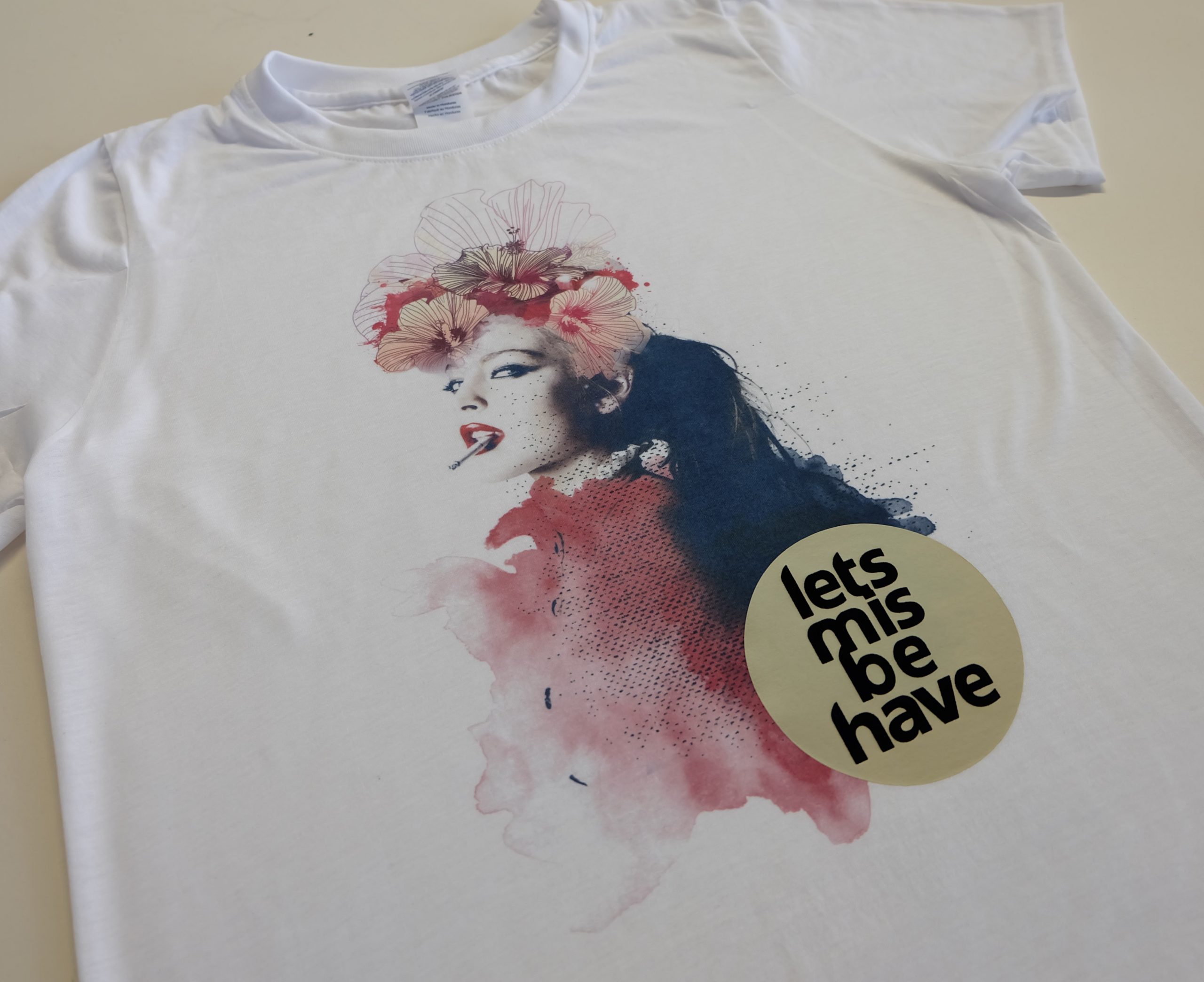Weißes T-Shirt mit Sublimationsdruck: Frauenporträt mit Blüten im Haar, Aquarellflecken in Rot und Blau, Schriftzug lets misbehave