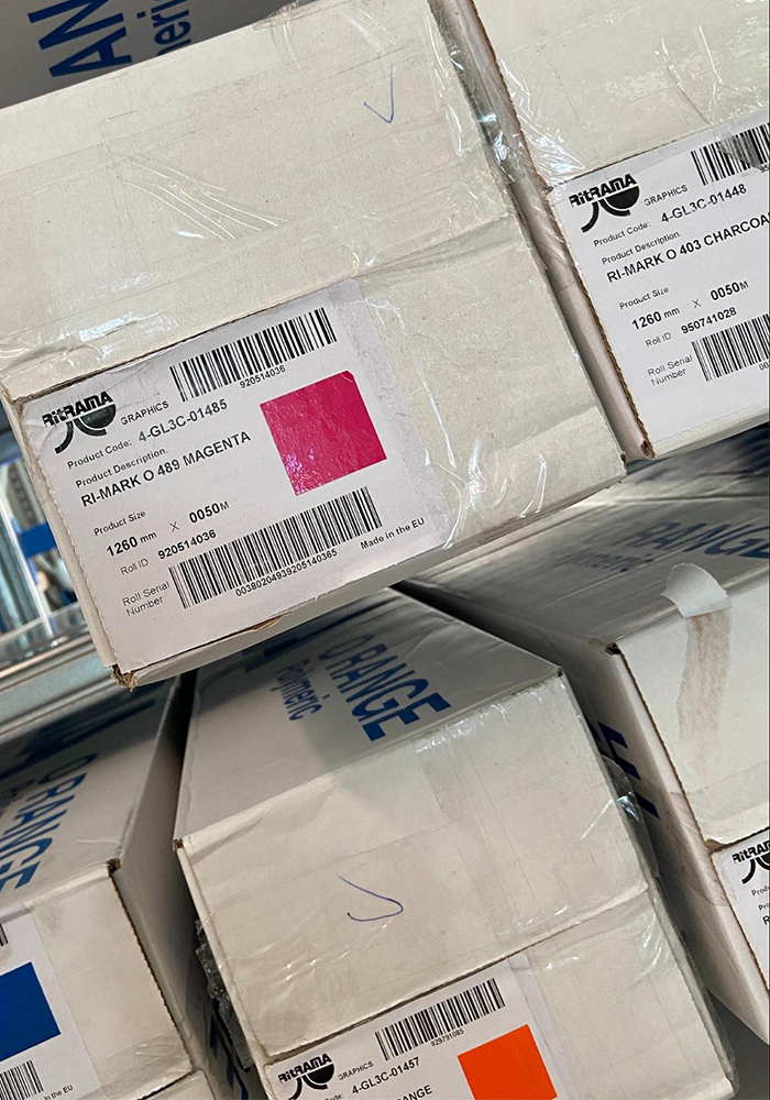Gestapelte Ritrama-Folienkartons mit Etiketten mit Produktcode, Roll ID und Barcodes, auf denen die Chargennummer zum Scannen steht