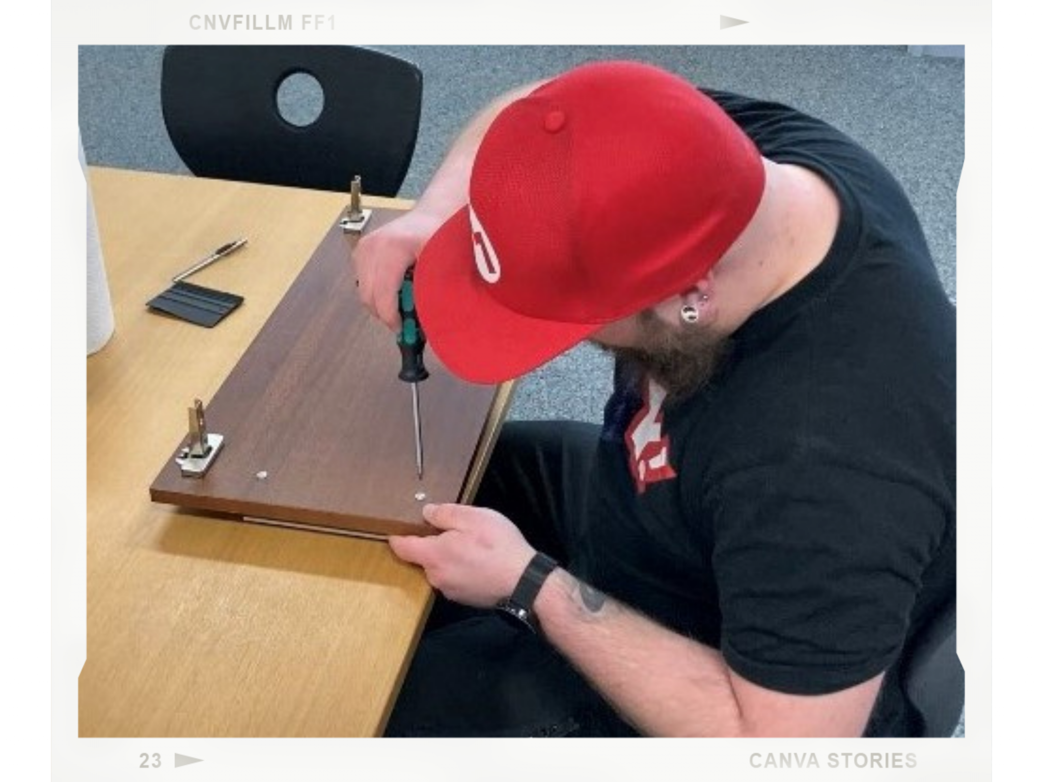 Mann mit roter Kappe schraubt den Griff von einer braunen Schranktür auf dem Tisch ab, daneben liegt ein Rakel für die Folienverklebung