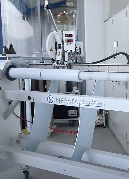 Rollenschneidemaschine NEPATA 1900 ADWS teilt eine Folienrolle der Breite nach in zwei schmalere Rollen, etwa für häufig verkaufte Breiten