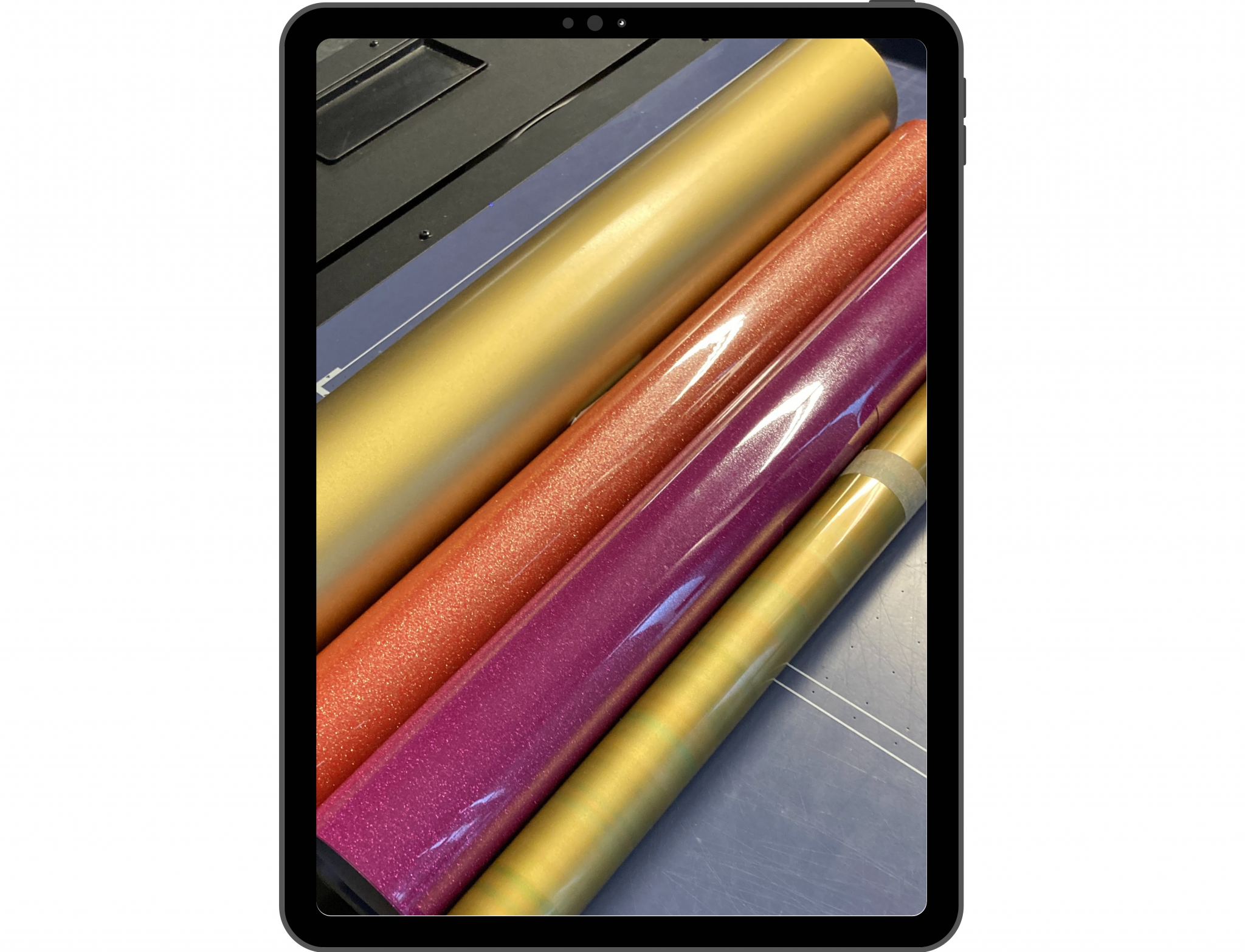 Tablet-Mockup mit Rollen Flexfolie in Gold, Orange- und Pink-Glitzer sowie Gold-Metallic auf einem Schneideplotter zur Textilveredelung