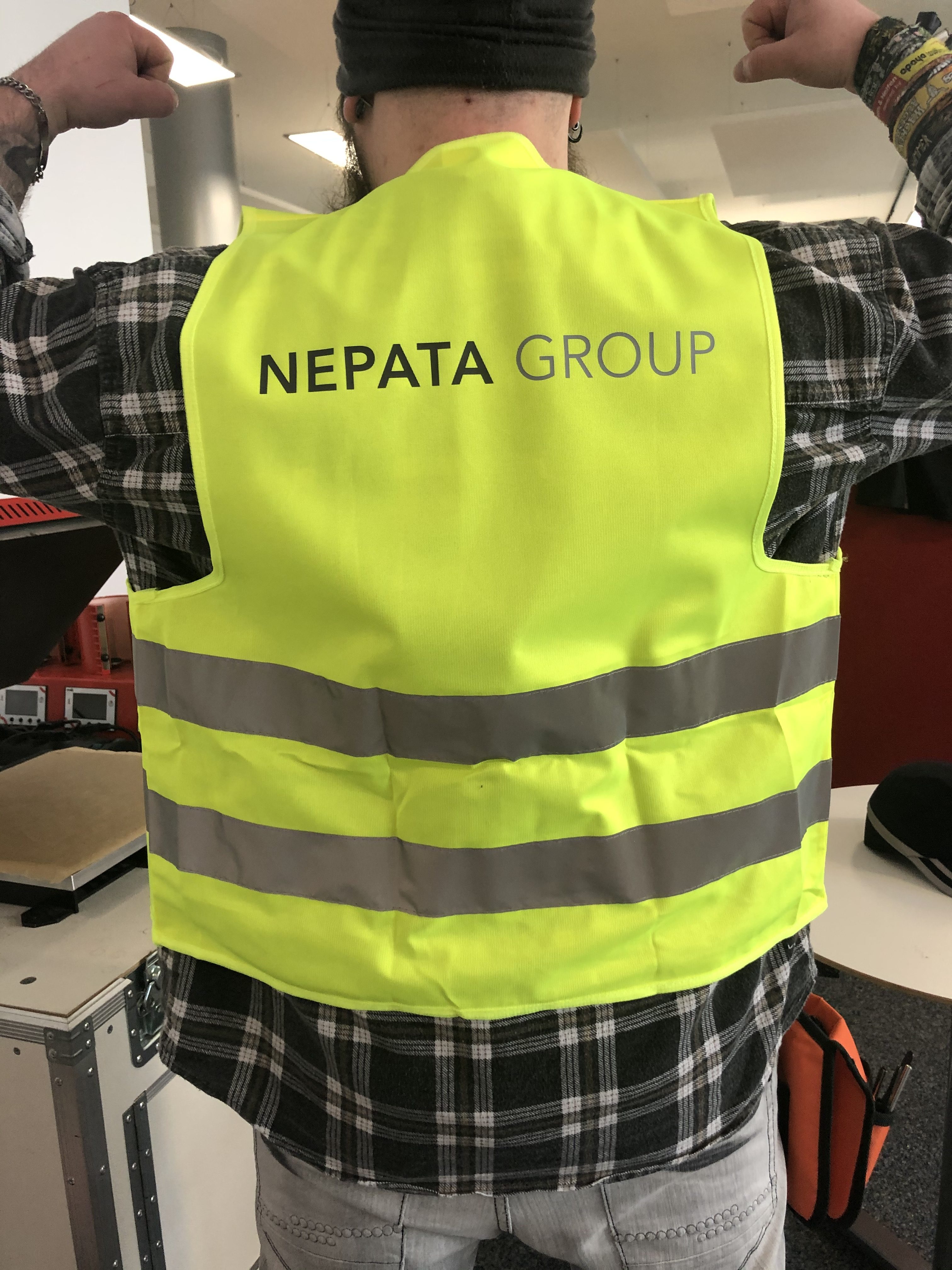 Person von hinten in neongelber Warnweste mit zwei Reflexstreifen, auf dem Rücken individuell bedruckt mit dem Schriftzug NEPATA GROUP