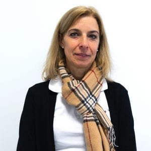 Porträt von Simone Zopik, Sales Managerin im Vertrieb der Nepata GmbH, mit blondem Haar, schwarzer Strickjacke und kariertem Schal vor weißer Wand