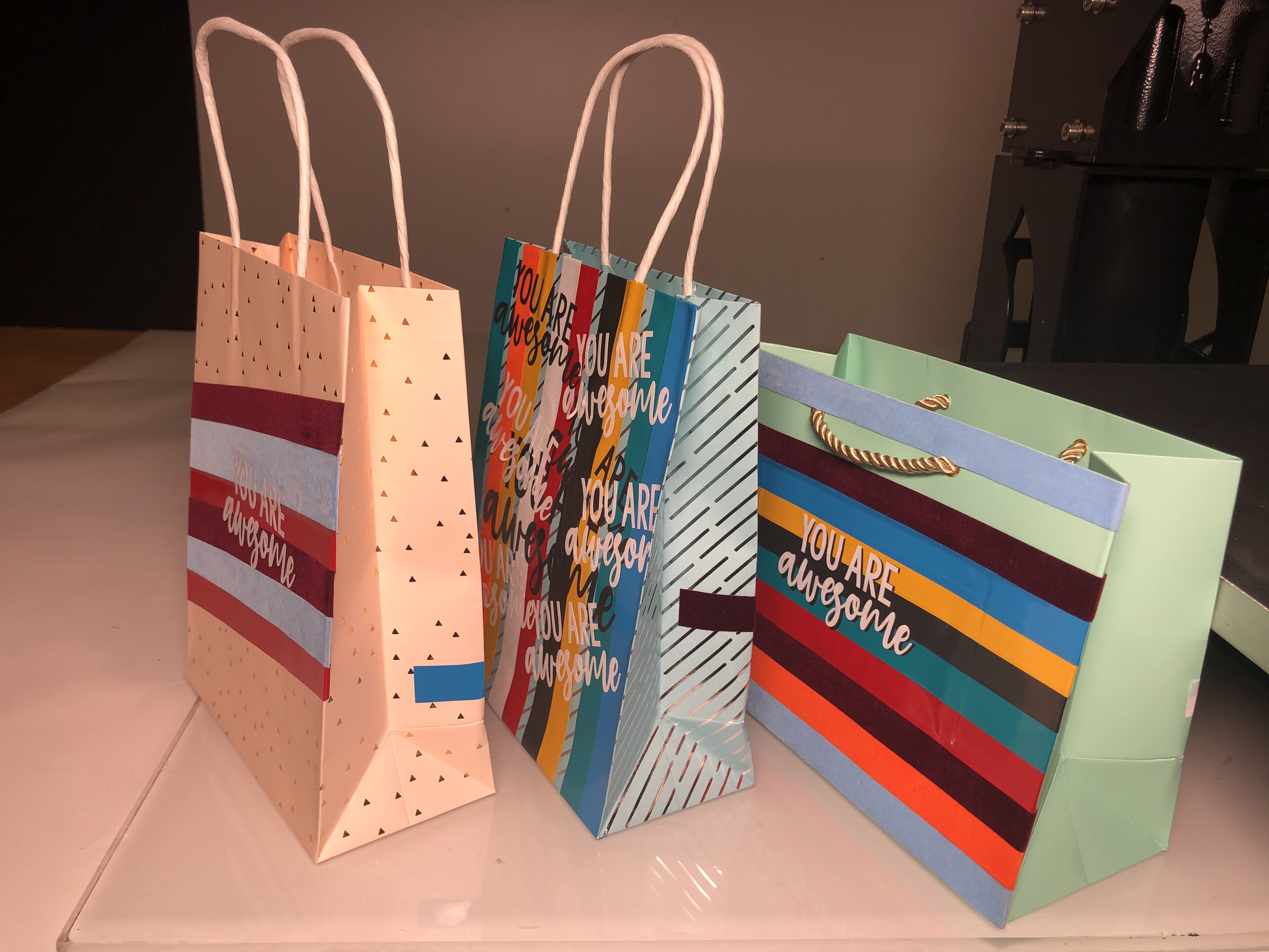 Drei fertig beklebte Geschenktüten mit bunten Streifen und der Schrift You are awesome aus Selbstklebefolie