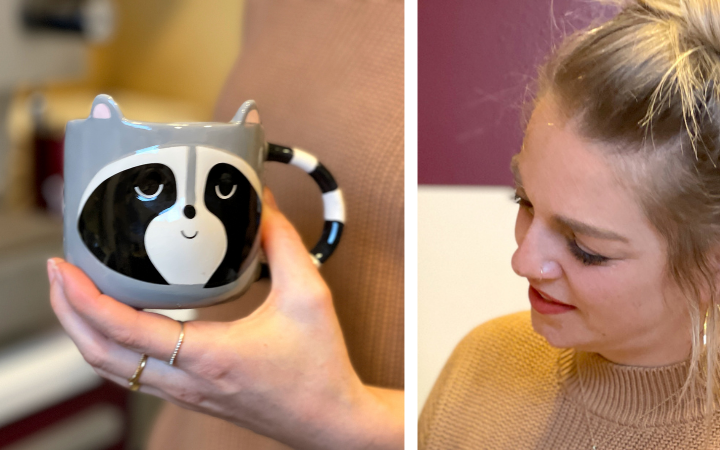Zweigeteilt: Sabrinas Hand hält eine graue Waschbär-Tasse mit gestreiftem Henkel, rechts lächelt Sabrina im beigen Rollkragenpullover