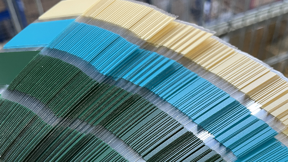 Bandes de couleur fabriquées à la machine à partir d'un film vinyle en vert, bleu turquoise et jaune clair, empilées les unes contre les autres sur un support transparent destiné aux nuanciers
