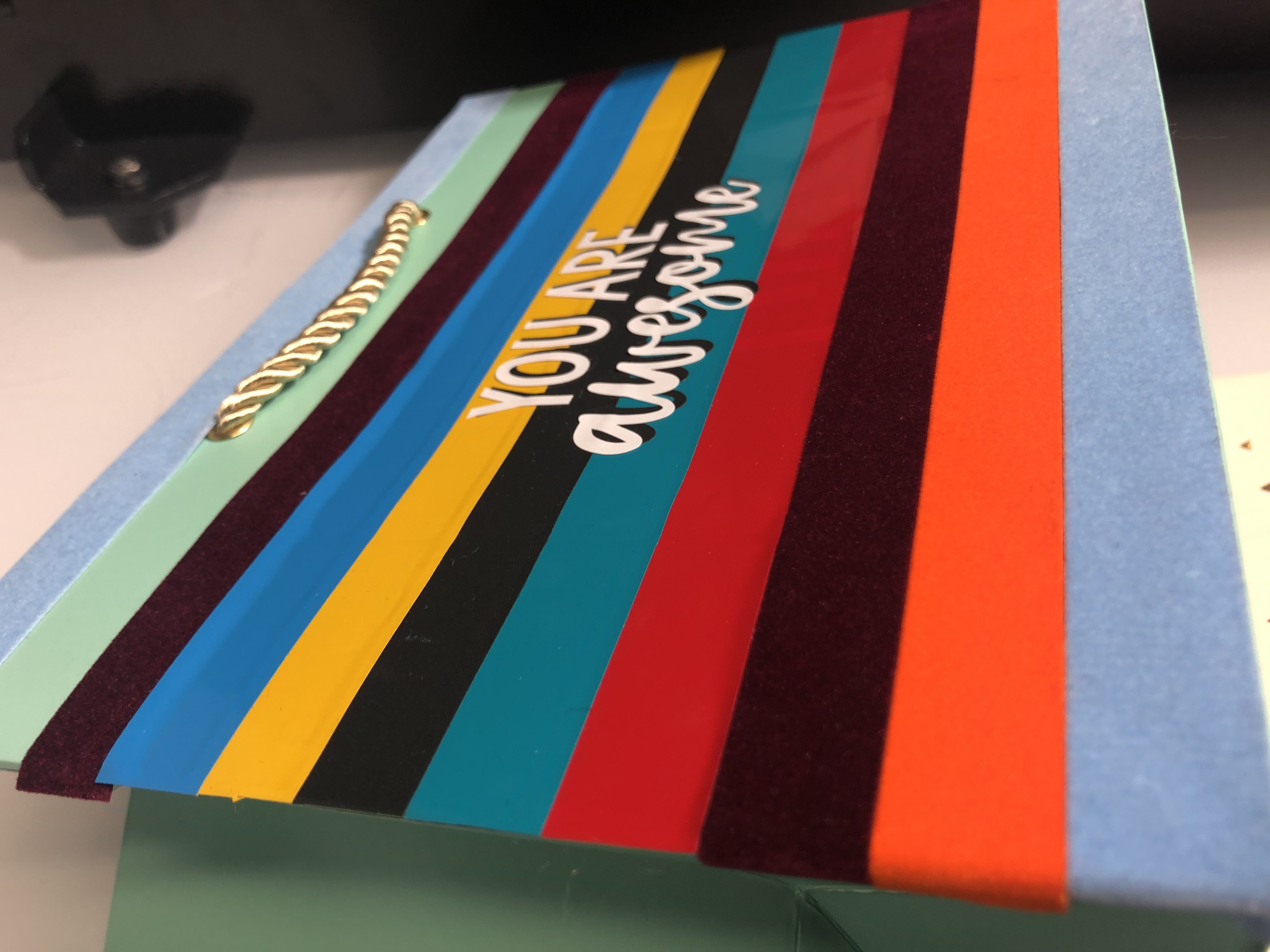 Mintgrüne Geschenktüte mit bunten Streifen aus Selbstklebefolie, teils in Samtoptik, und weißem Schriftzug YOU ARE awesome