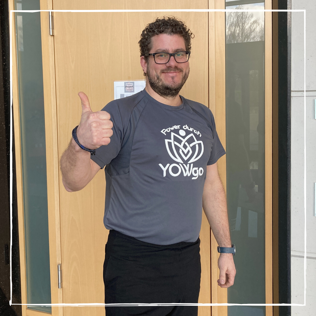 Chef Bernhard zeigt Daumen hoch im grauen T-Shirt mit weißem Aufdruck Power durch YOWgo aus der YOWGA-Kollektion