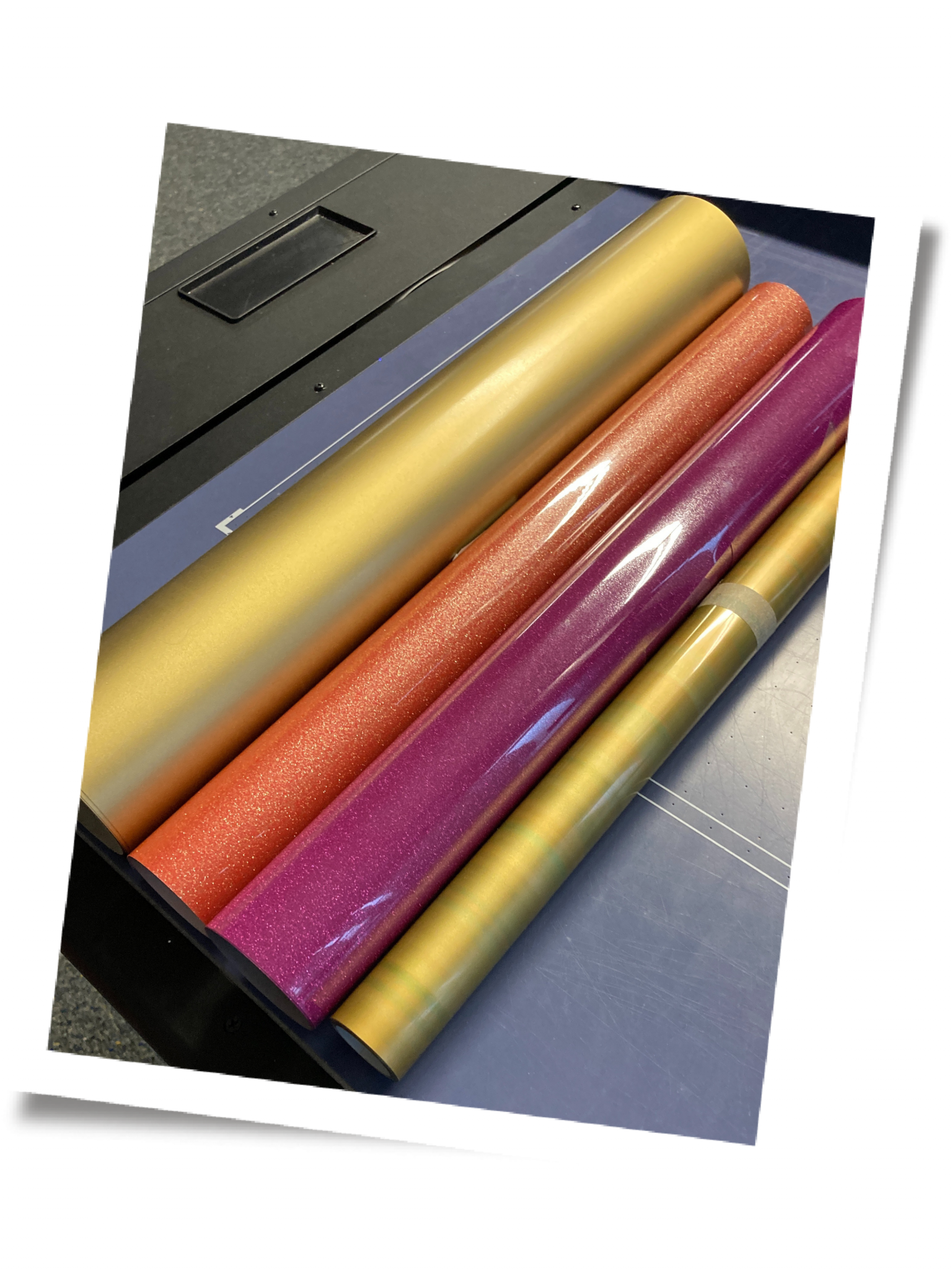 Vier Rollen Transferfolie in Gold, Orange-Glitter, Magenta-Glitter und Metallic-Gold auf einem Plotter, die Folien für die Adventssäckchen