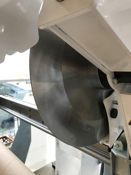 Runde 5-mm-Abstechklinge einer NEPATA-ADWS-Maschine mit großflächig schrägem Schliff unter weißem Gehäuse, darunter eine Papphülse