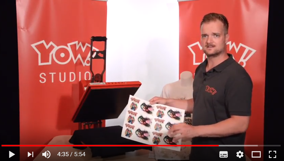 Videostill: Mann im YOW! Studio zeigt Bogen mit bunten READY Transfermotiven neben einer roten Transferpresse