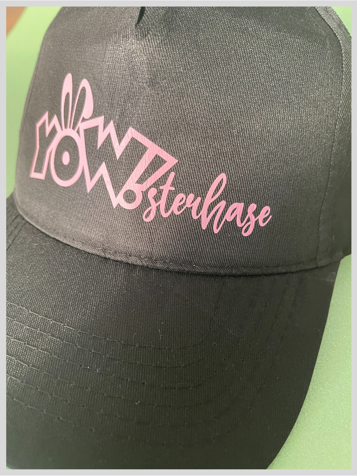 Schwarze Cap mit rosa Flexfolien-Aufdruck: YOW!-Logo mit Hasenohren und Schriftzug sterhase, zusammen YOWsterhase