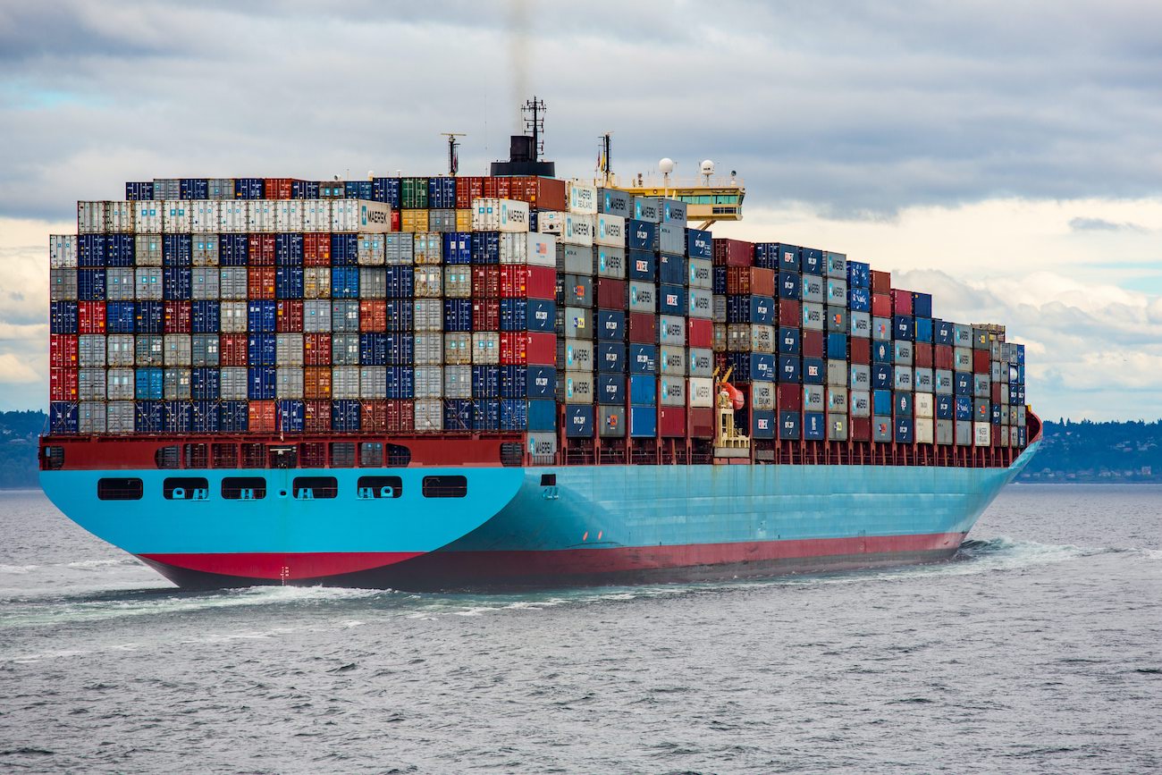 Un porte-conteneurs à pleine charge, à la coque bleu clair, en mer, symbole du transport maritime de films vinyles en provenance d'Asie