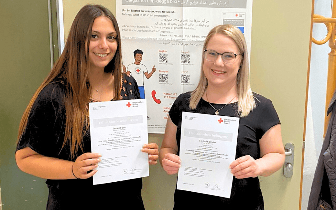 Jessica Erb and Stefanie Binder smile as they show their certificates of attendance from the Bavarian Red Cross for the first-aid training course