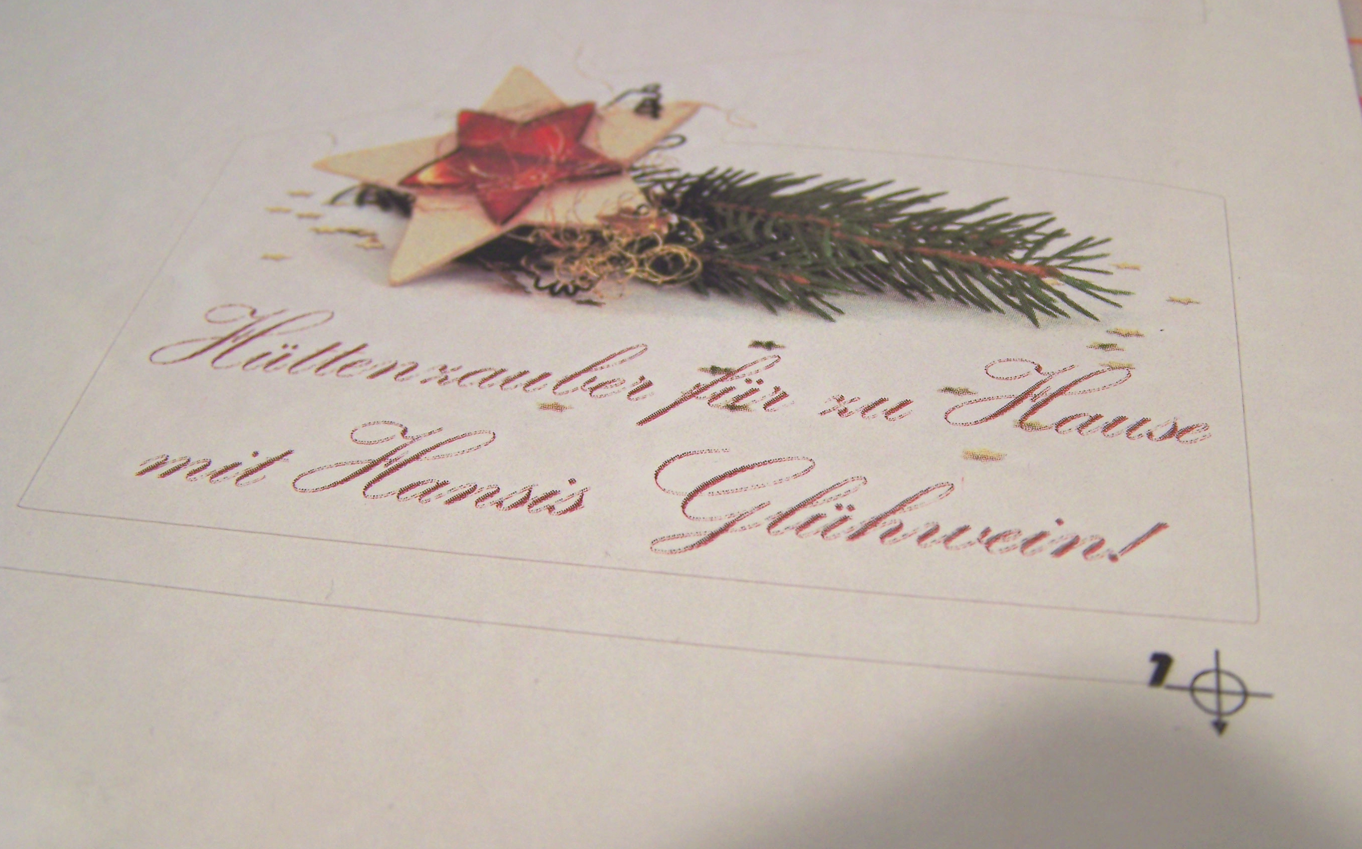 Geplottetes Glühwein-Etikett mit Stern, Tannenzweig und Schriftzug Hüttenzauber für zu Hause, daneben eine Passermarke auf der Laserfolie