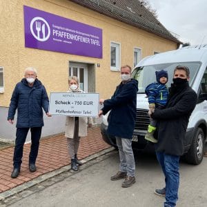 Scheckübergabe der Nepata Group über 750 Euro an die Pfaffenhofener Tafel, Personen mit Masken vor dem Tafelgebäude, ein Mann trägt ein Kind