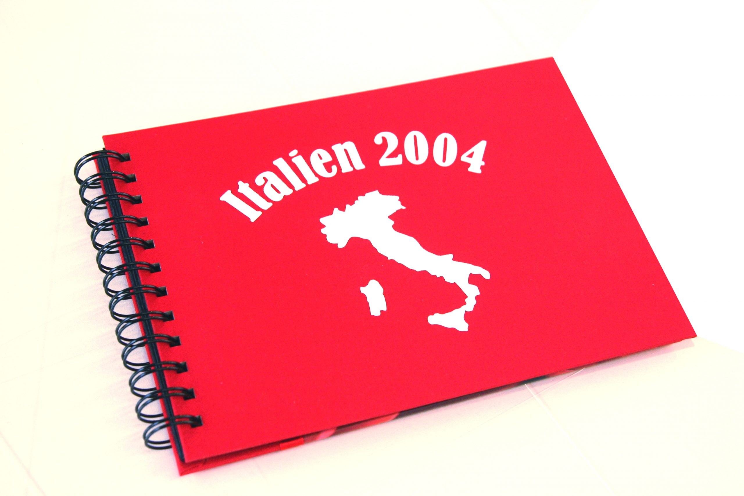 Rotes Fotoalbum mit Spiralbindung, beschriftet mit weißer selbstklebender Flockfolie: Schriftzug Italien 2004 und Umriss Italiens