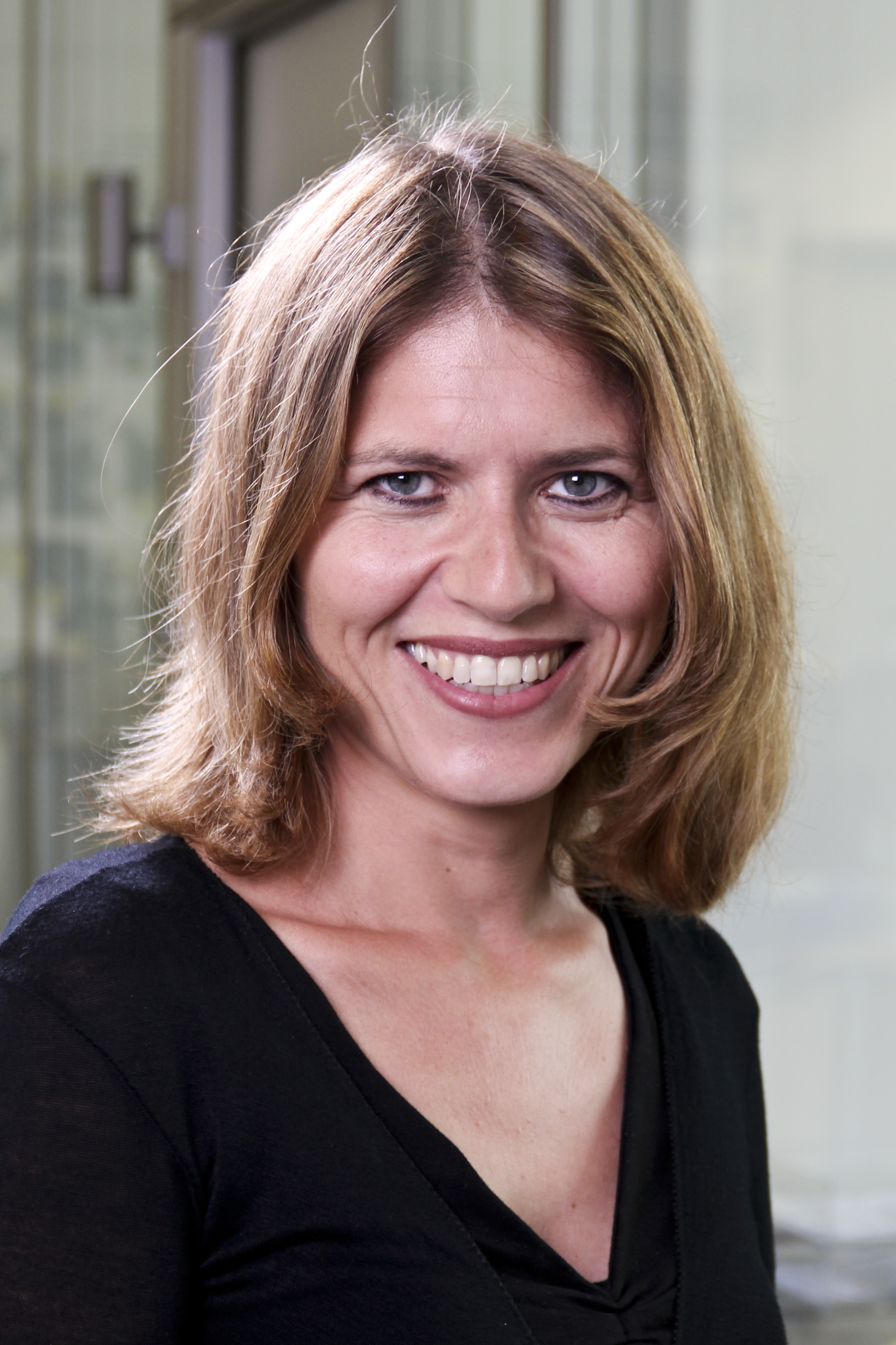 Porträt der neuen YOW! Mitarbeiterin Dr. Simona Collin, lächelnd, mit schulterlangem rotblondem Haar und schwarzem Oberteil