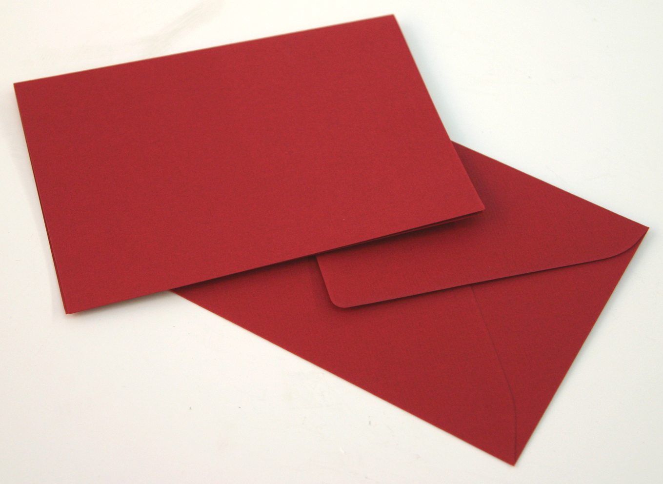 Unbedruckte rote Klappkarte und passendes rotes Kuvert auf weißem Grund – Ausgangsmaterial für selbst gestaltete Weihnachtskarten