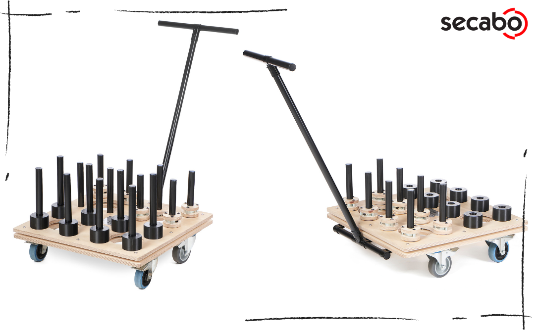 Zwei rollbare SECABO Storage Carts aus Holz mit T-Griff-Deichsel, Lenkrollen und schwarzen Steckdornen zum Aufstecken von Materialrollen