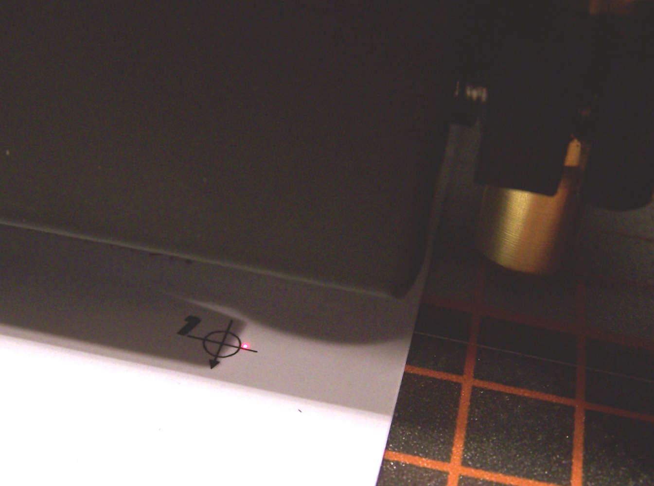 Schneideplotter tastet mit rotem Laserpunkt die Passermarke auf bedruckter Laserfolie ab, daneben Schneidkopf und Plotunterlage mit Raster