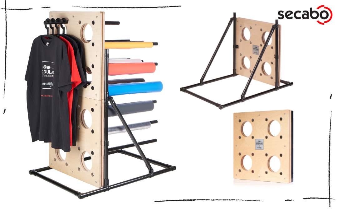 SECABO Vertical Shelving System mit T-Shirts und bunten Folienrollen, daneben Einzelgestell und Wandpaneel aus gelochtem Holz