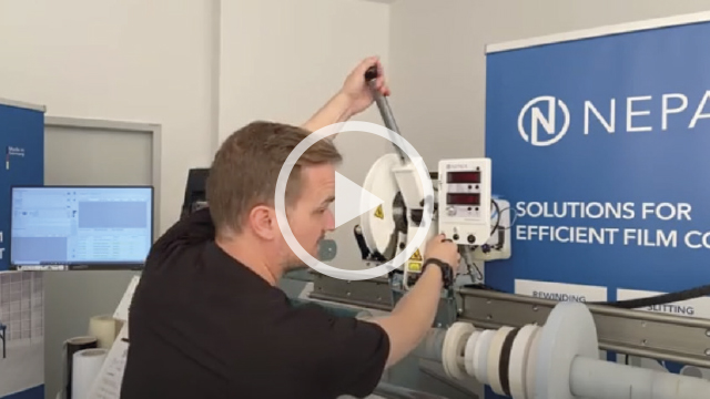 Vidéo : un employé utilise un levier pour amener la lame d'une machine de tronçonnage NEPATA contre un Rouleau de films vinyle afin d'obtenir des bords de coupe nets