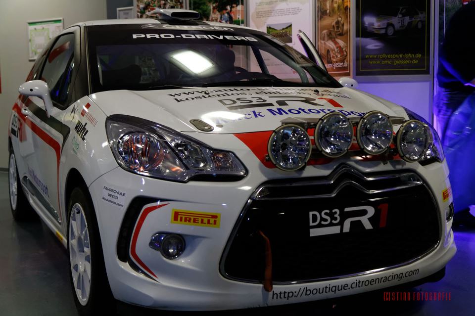 Weißer Citroën DS3 R1 Rallyewagen mit selbst geplotteten Beschriftungen und Sponsorenlogos in Rot und Schwarz bei der Präsentation