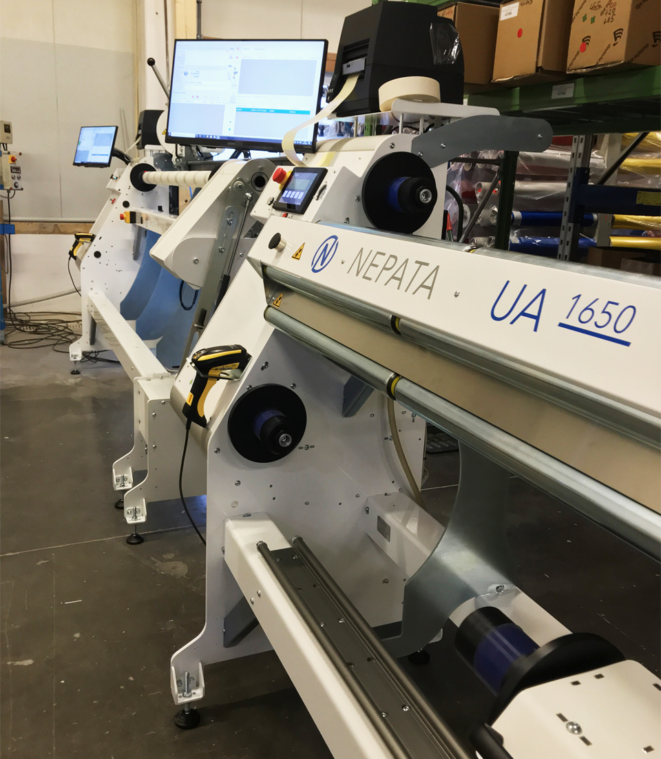 Deux machines NEPATA UA 1650 blanches, équipées d'un écran, d'une imprimante d'étiquettes et d'un lecteur de codes-barres, installées côte à côte dans un entrepôt