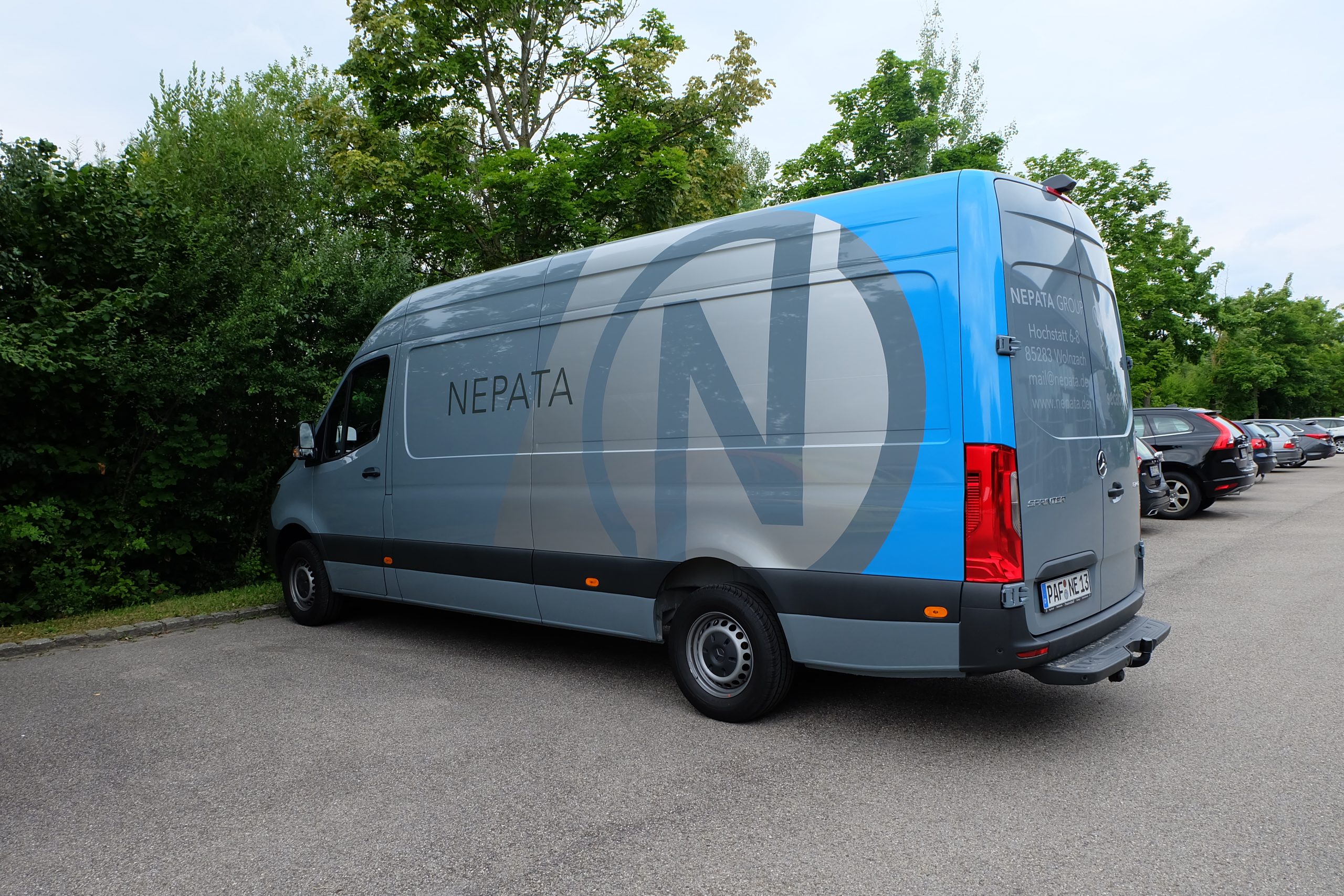 Grauer Transporter mit Beklebung: großes N-Logo und Schriftzug NEPATA an der Seite, blaues Heck mit Adresse und Kontaktdaten