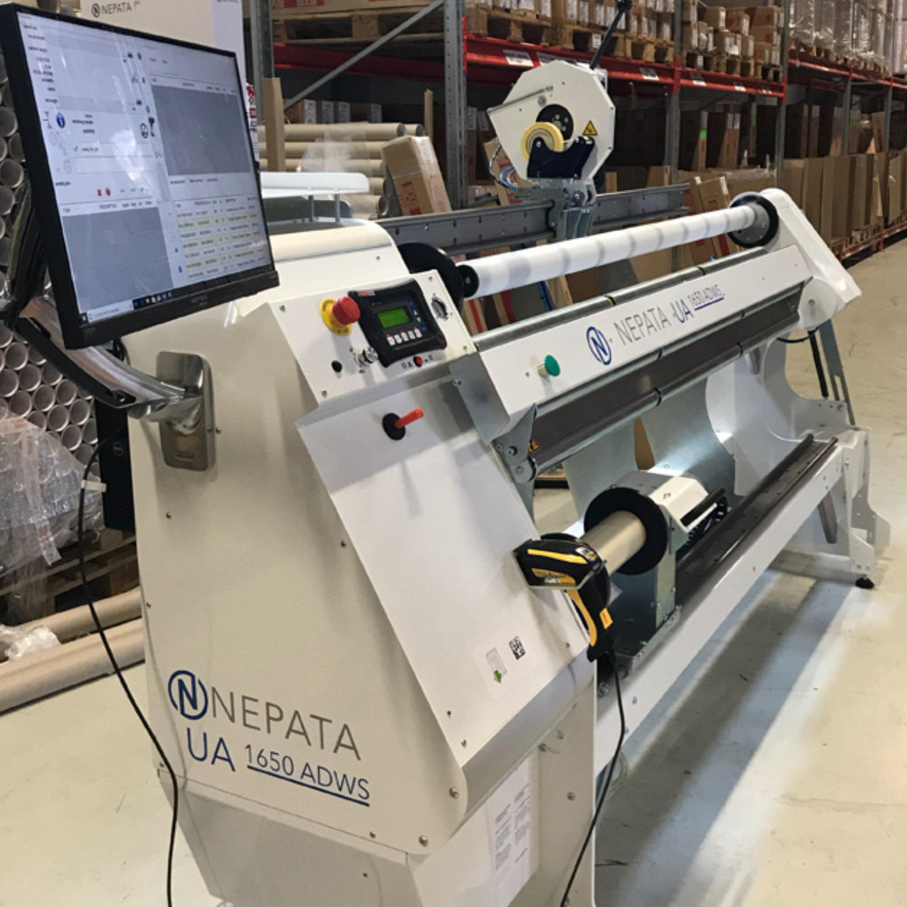 Folienumwickelmaschine NEPATA UA 1650 ADWS mit Bildschirm, Bedienfeld und Barcodescanner in einer Lagerhalle mit Regalen und Folienrollen