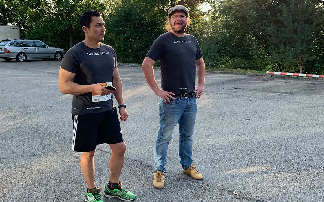 Läufer mit Startnummer und Zuschauer in grauen Nepata-Group-Teamshirts auf einem Parkplatz beim virtuellen Firmenlauf 2020 Ingolstadt
