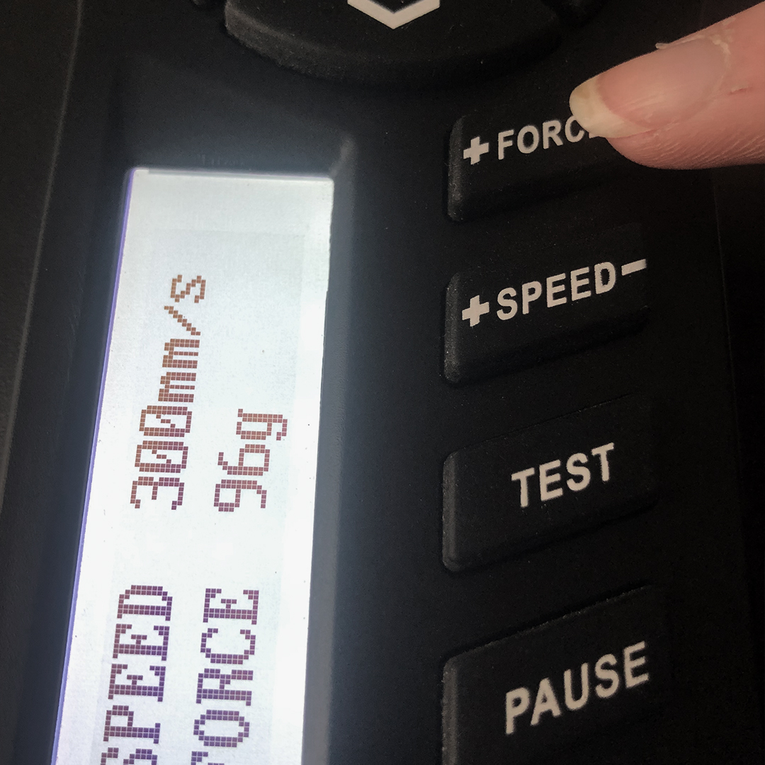 Finger drückt die FORCE-Taste am Bedienfeld des Schneideplotters, Display zeigt Schnittgeschwindigkeit 300 mm/s und Andruck 96 g