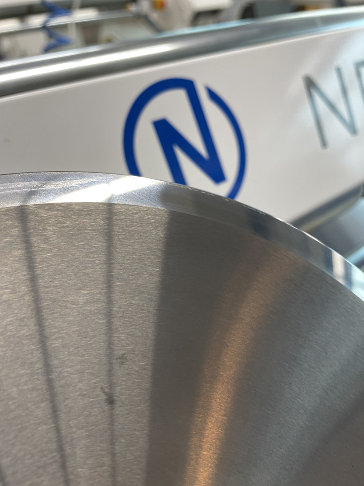 Nahaufnahme einer runden Klinge aus Vollhartmetall mit geschliffener Schneidkante, im Hintergrund eine NEPATA-Maschine mit Logo