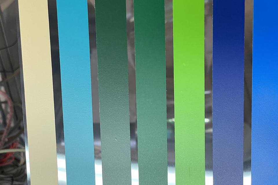 Parallele Plotterfolienstreifen in Beige, Hellblau, Grün- und Blautönen, maschinell nebeneinander auf transparente PE-Folie geklebt