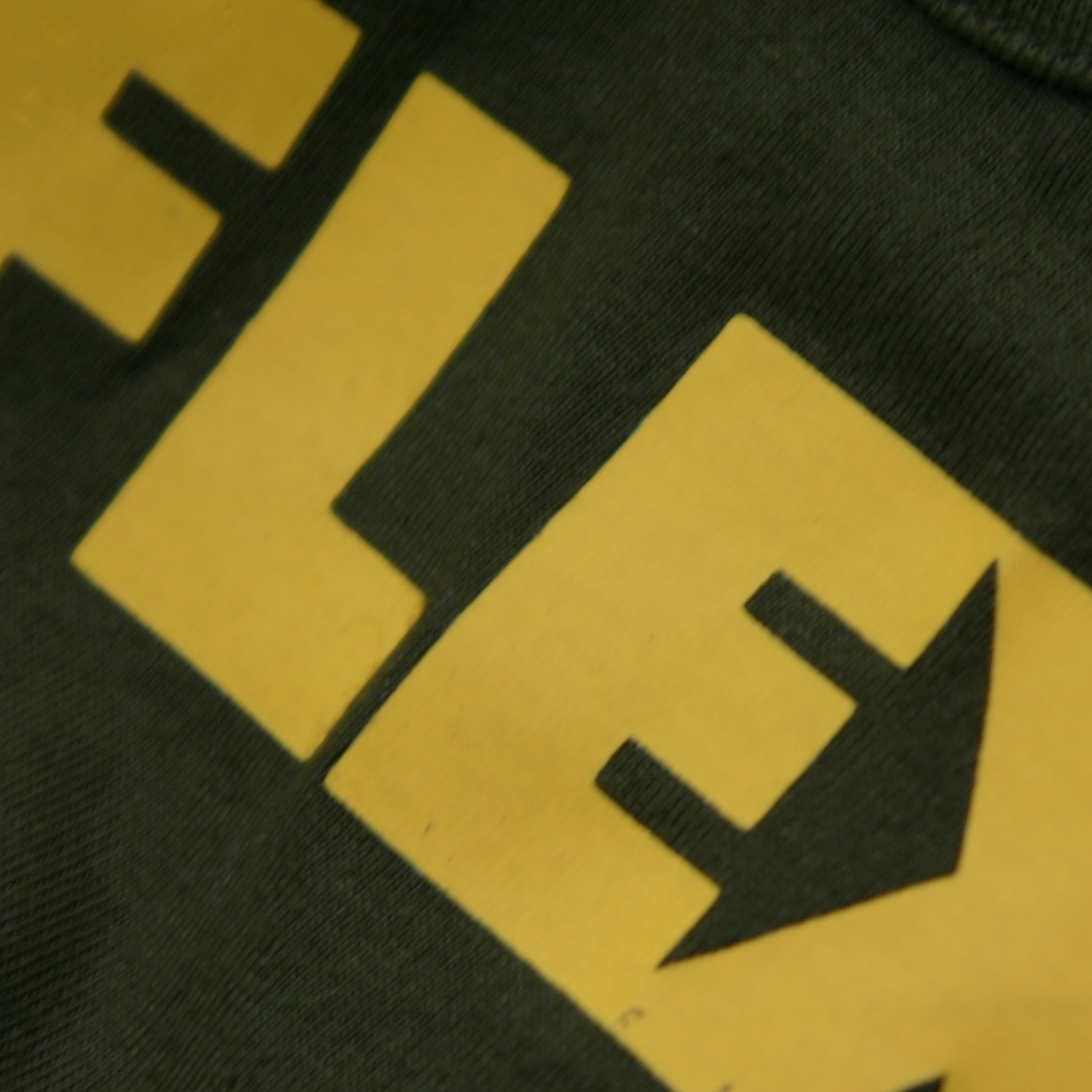 Nahaufnahme: gelbe Flexfolie mit dem Schriftzug FLEX auf dunklem Textil, glatte Oberfläche und saubere Schnittkanten der geplotteten Buchstaben