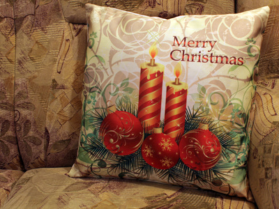 Bedrucktes Kissen mit Weihnachtsmotiv aus Kerzen, roten Kugeln und Tannenzweigen sowie Merry Christmas als Idee für personalisierte Kissenbezüge