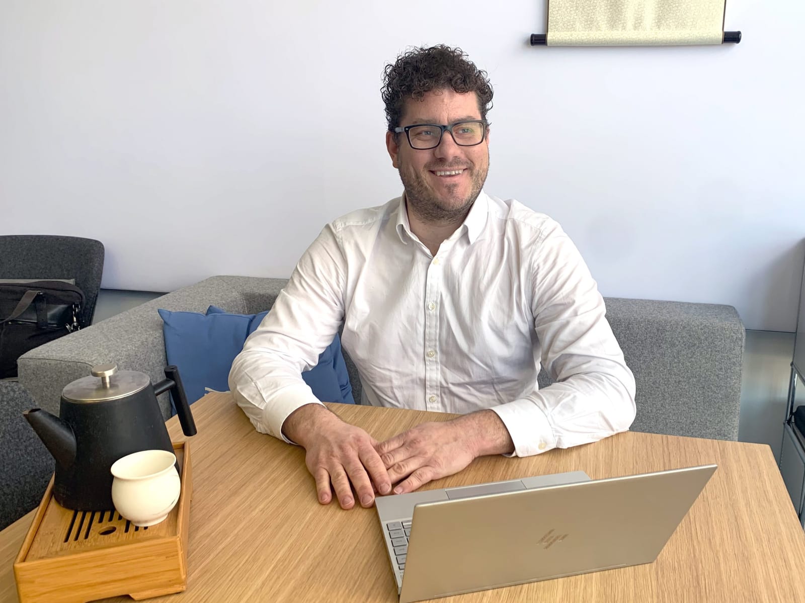 Nepata’s managing director, Bernhard Schmidt, smiling in a white shirt at a wooden table with a laptop and a teapot in a bright meeting room