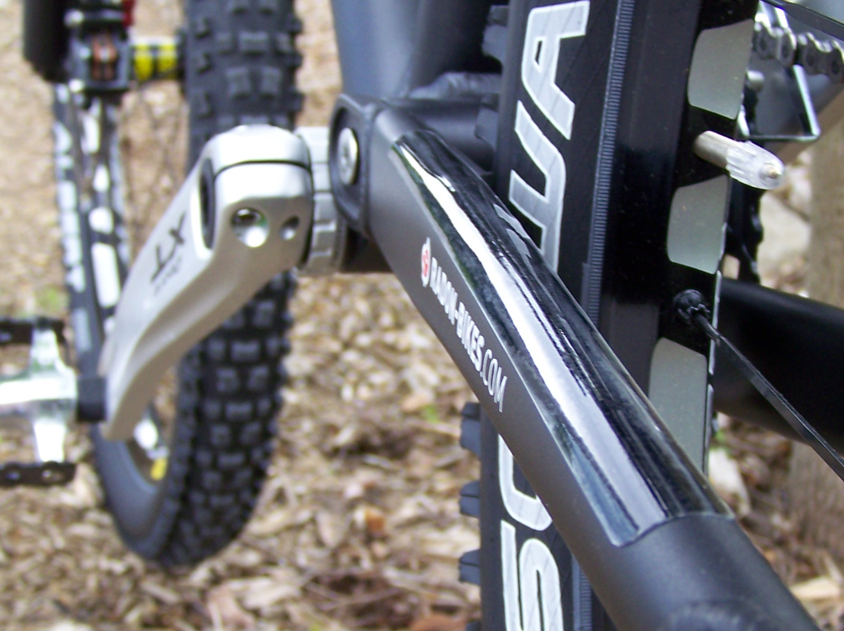 Transparente Steinschlagschutzfolie auf der Kettenstrebe eines grauen Mountainbikes, daneben Kurbel und Hinterrad in Nahaufnahme