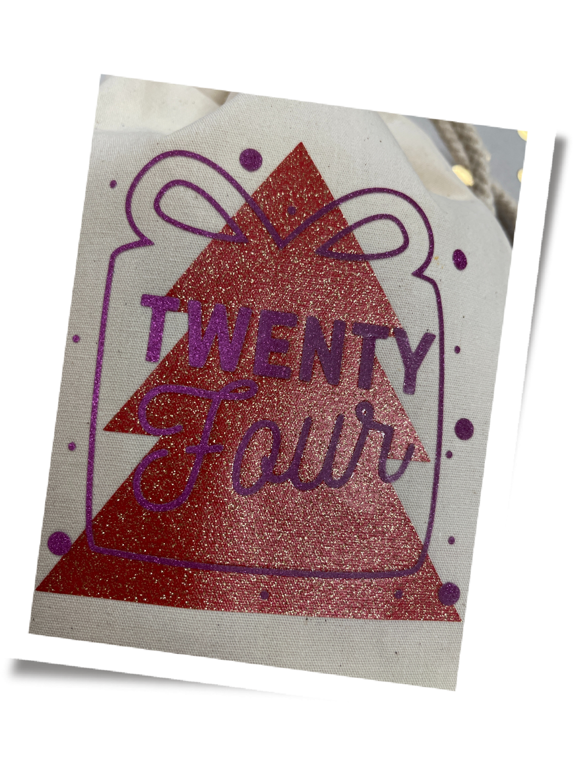 Stoffbeutel mit fertig verpresstem Motiv: rotes Glitzerdreieck als untere Folienschicht, darüber lila Geschenk-Umriss mit Twenty Four