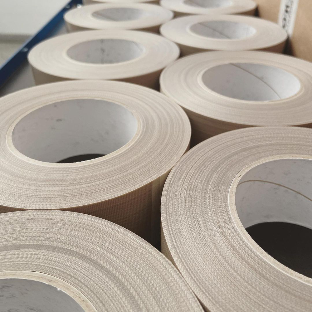 Mehrere abgestochene Tape-Rollen aus PTFE-beschichtetem Glasgewebe auf Kartonkernen, mit glatten, sauberen Schnittkanten