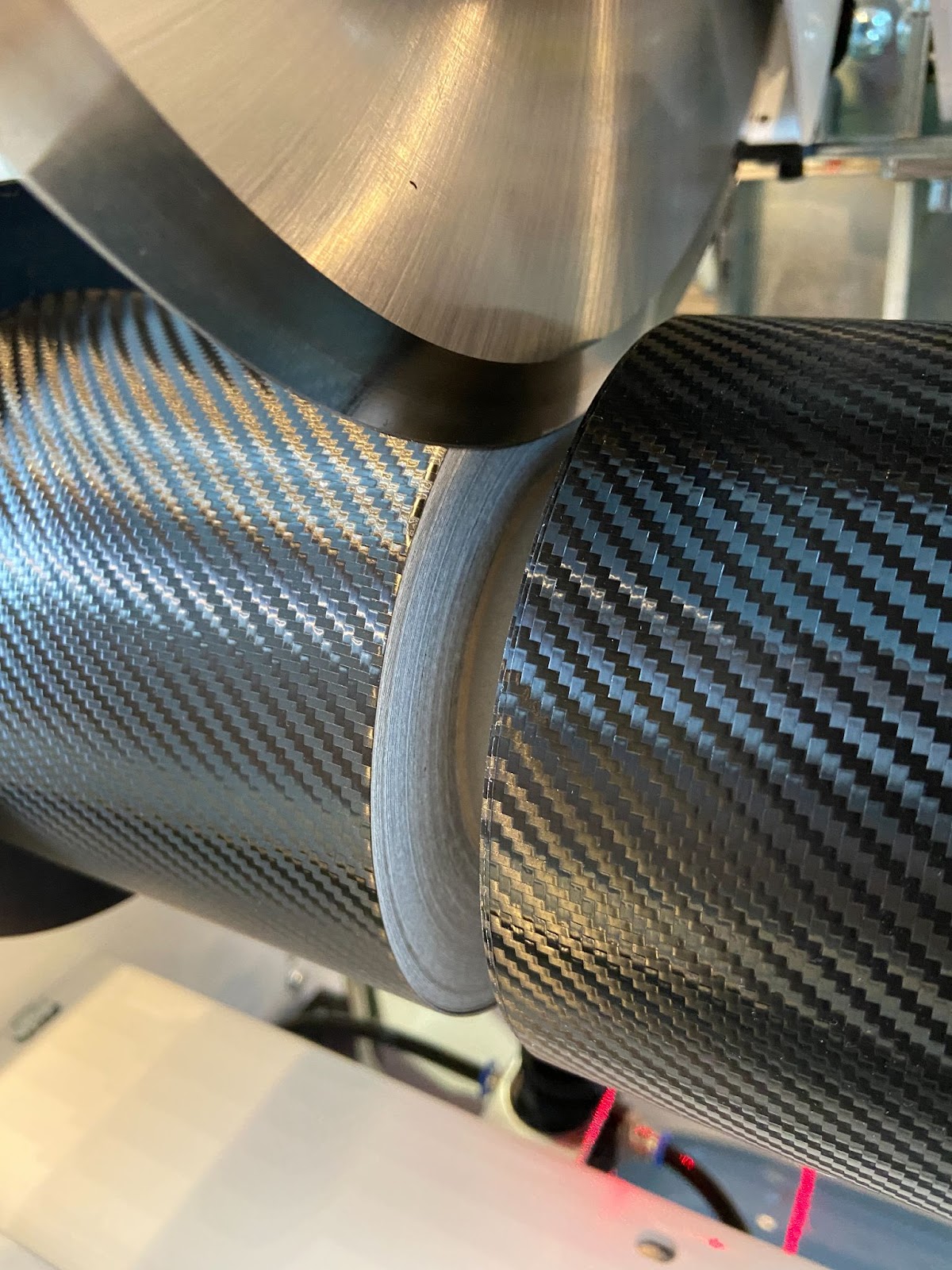 Rundmesser der NEPATA sticht eine Rolle gegossener Carbonfolie ab, sauber getrennte Schnittkante, rote Laserlinie zur Positionierung