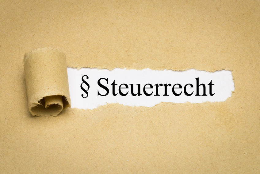 Aufgerissenes braunes Packpapier gibt den Schriftzug § Steuerrecht auf weißem Untergrund frei